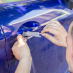Young,Man,Opening,Blue,Car,Door,With,Lock,Picker.